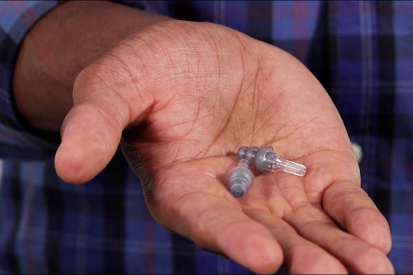 A man demonstrating the correct way to use pre-molded earplugs to help prevent noise-induced hearing loss.